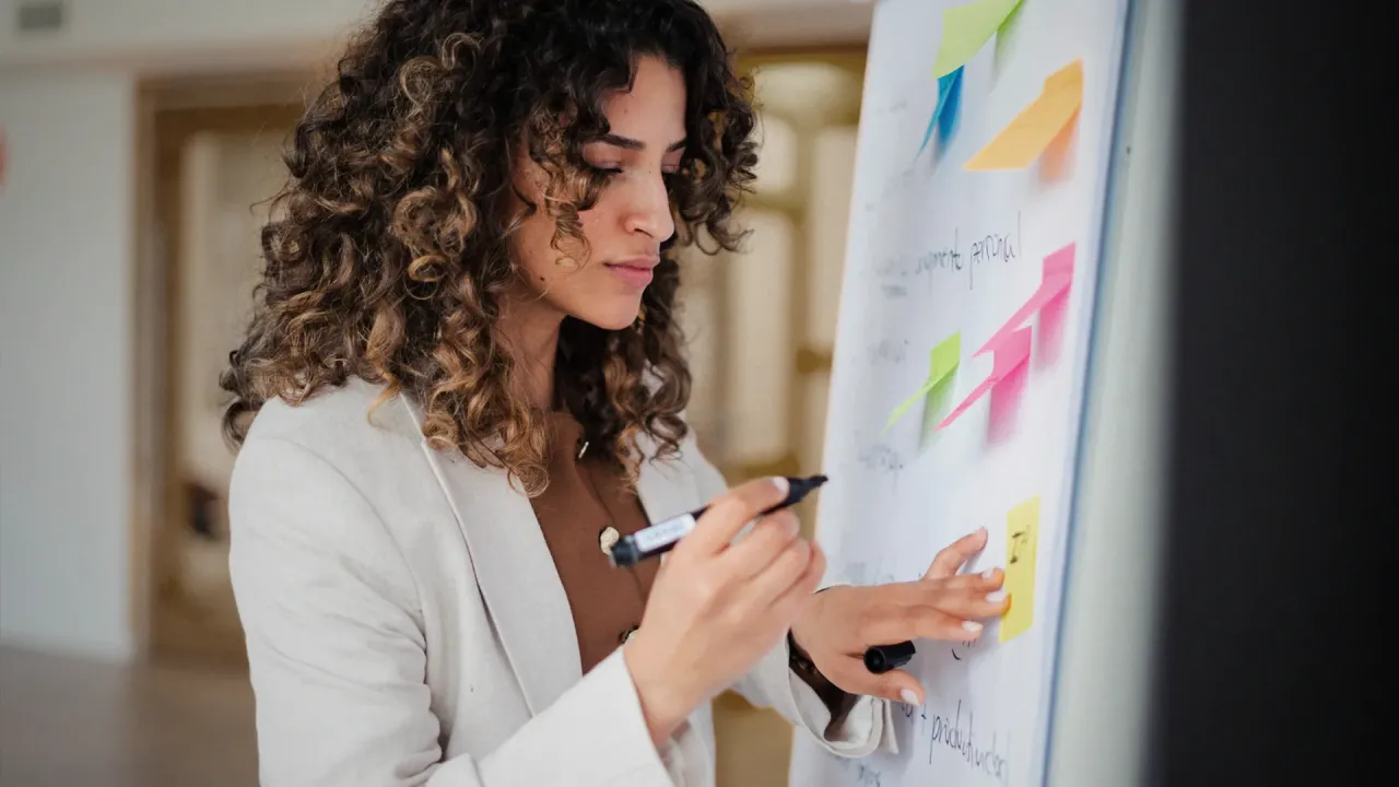 Frau, die an einem Whiteboard mit Post-Its arbeitet 