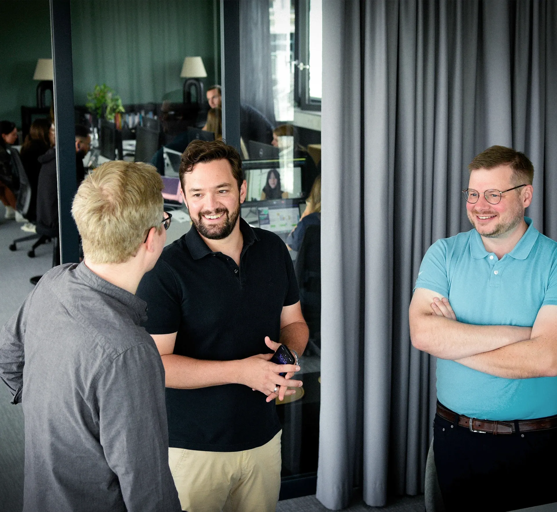 Geschäftsführende im Gespräch. Im Hintergrund das Team bei der Arbeit im Office