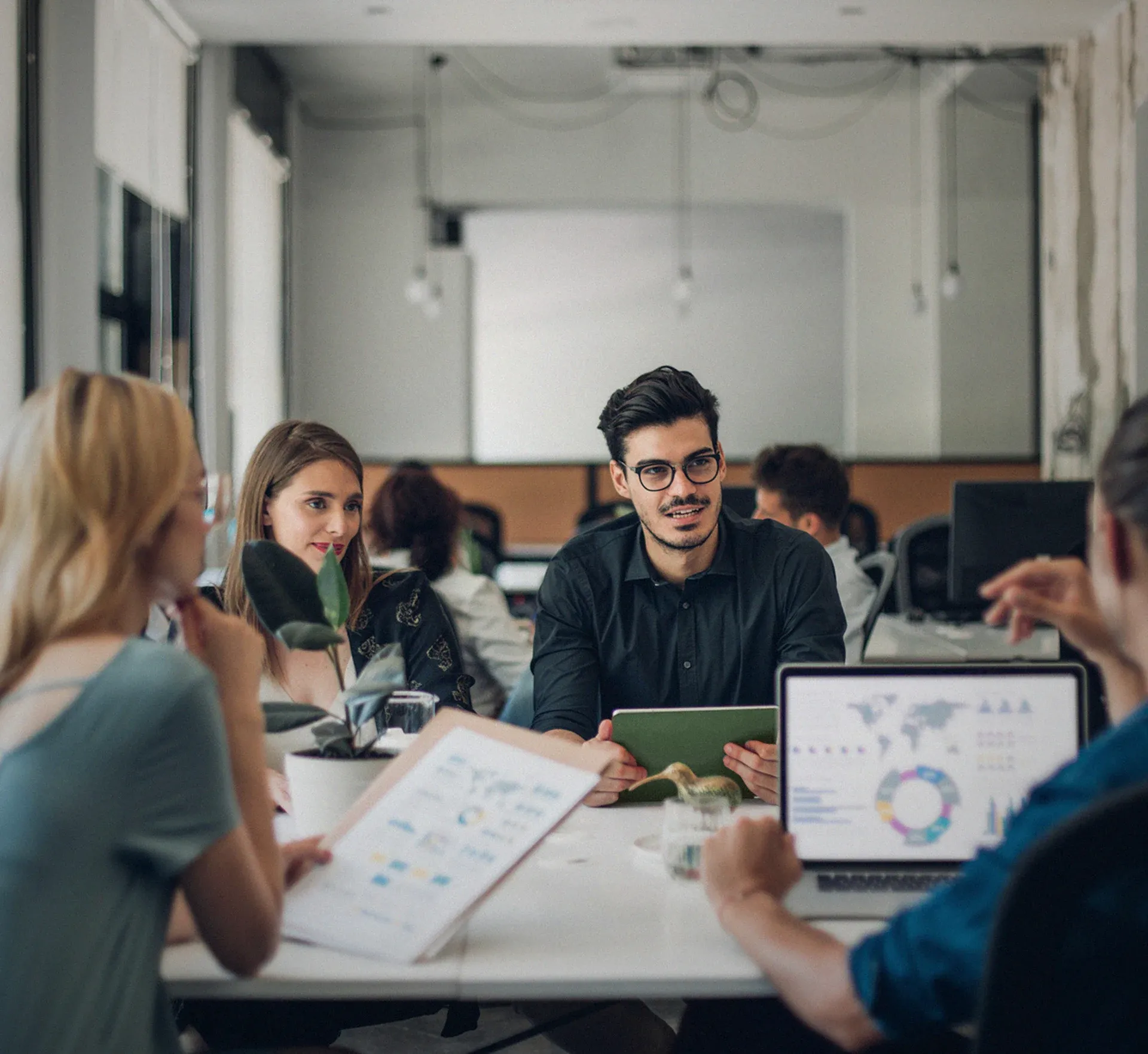 Team an einem Arbeitstisch mit Statistiken am Laptop
