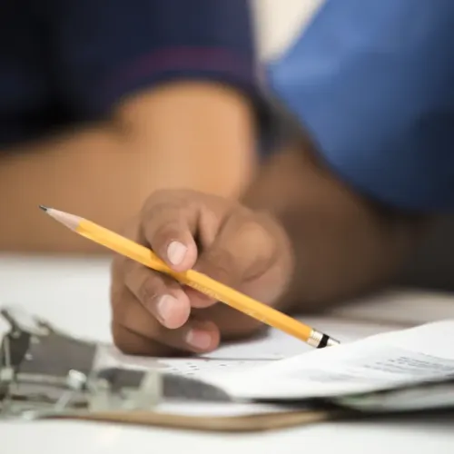 Person füllt handschriftlich ein Formular auf einem Klemmbrett aus